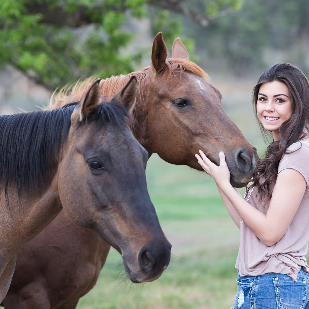 Young woman petting horse in field