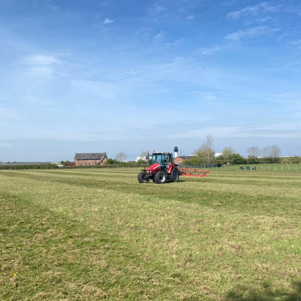 Large field with red tractor and machinery